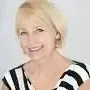 Joan Coullahan is wearing a black and white striped shirt and smiling.
