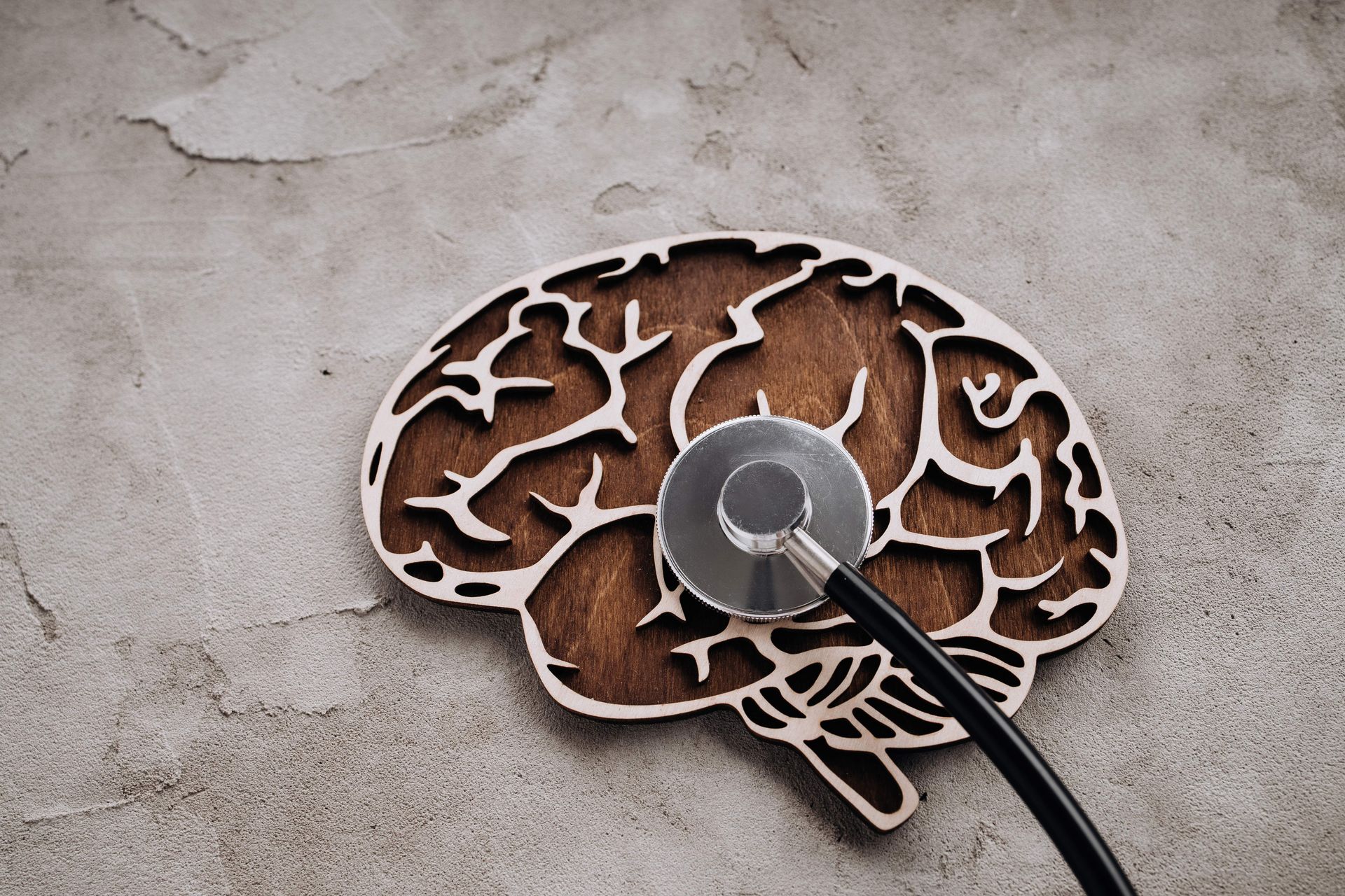 Stethoscope placed on a wooden brain cutout symbolizing mental health assessment.