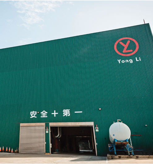 一座綠色的工業建築,有永利標誌、寬敞的入口,牆上還有「安全第一」的漢字。