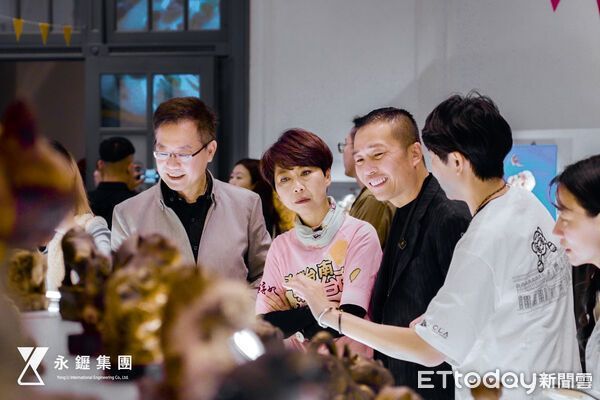 一群人聚集在一個明亮的空間裡,仔細欣賞展出的金色小雕像。