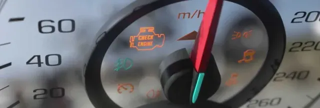 A close up of a speedometer with a yellow light on it.