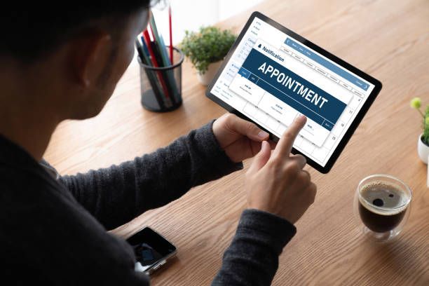 Person using a tablet to manage appointments. The word 