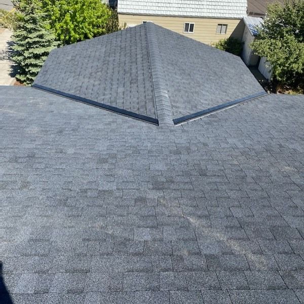 Overhead view of a dark gray asphalt shingle roof on a house, angled upward.