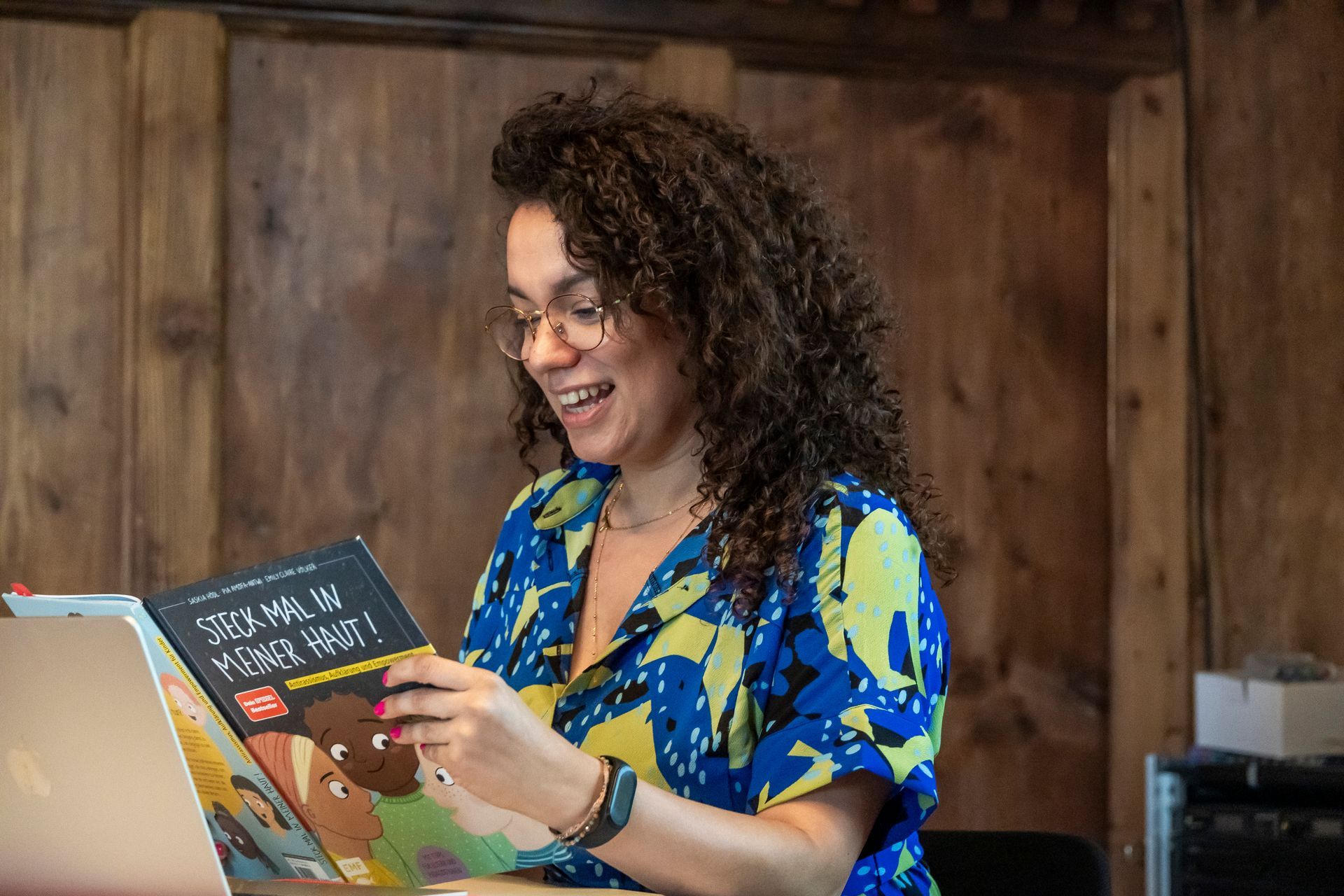 Eine Frau sitzt an einem Tisch und liest ein Buch.