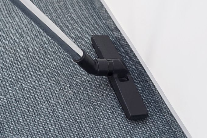 A vacuum cleaner is cleaning a carpet in a room.