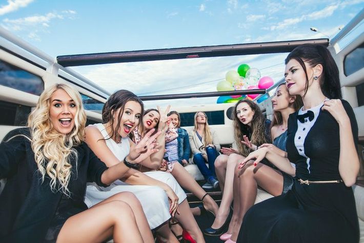 Young beautiful happy women celebrate bachelorette party in a convertible limousine