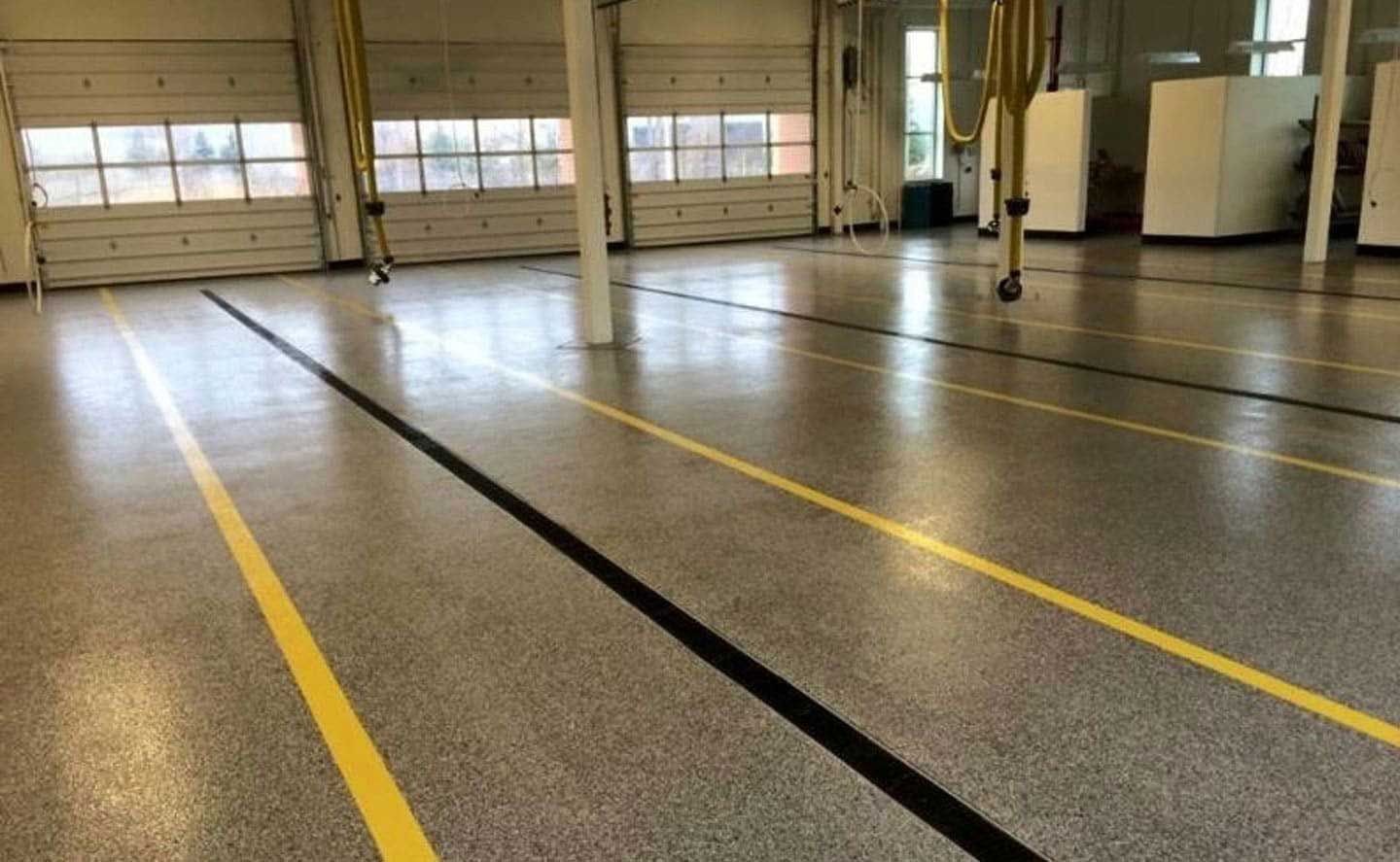 Empty industrial floor with yellow lines and large windows in the background