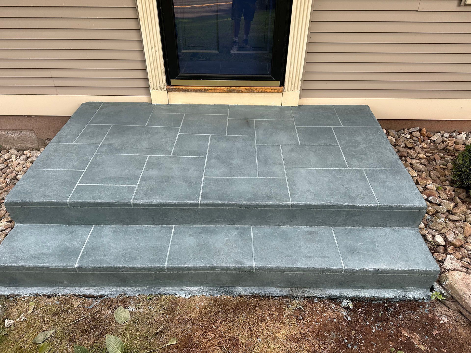 Front steps with gray stone pavers leading to a beige house entrance