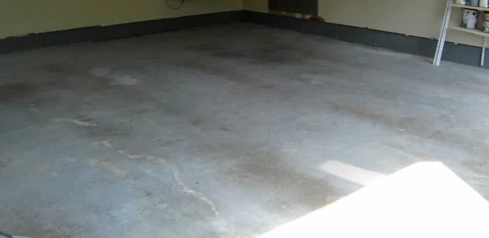 Empty concrete garage floor with a bright patch of sunlight in the lower right corner.
