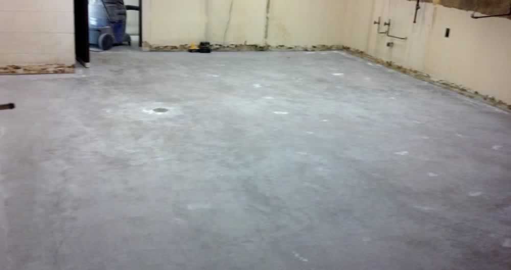 Empty concrete indoor space with beige walls and a blue object near the far left corner.