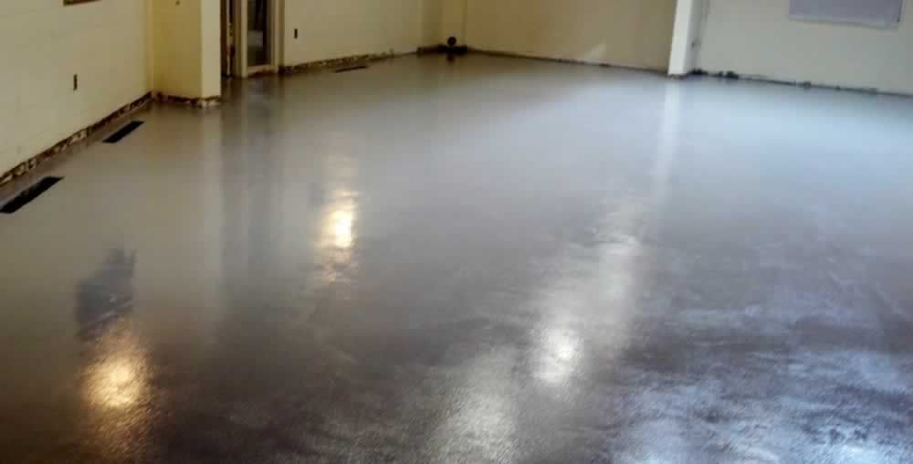Empty beige room with a glossy gray floor and windows along the left wall
