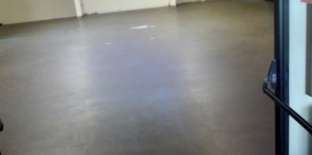 Empty gray floor in a hallway or room, seen near an open doorway with a black frame