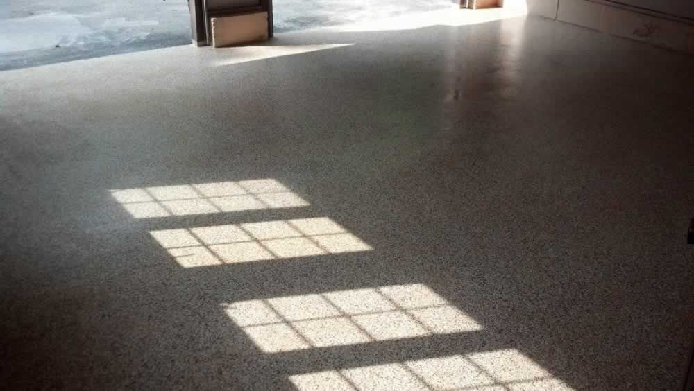 Sunlight forms bright window-paned rectangles on a gray floor in an empty room