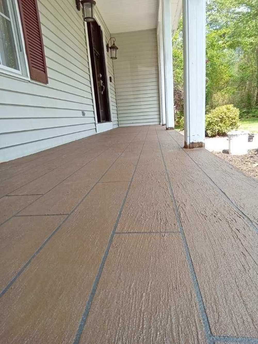 Covered front porch with tan wood-look flooring, white siding, and a doorway at the end.