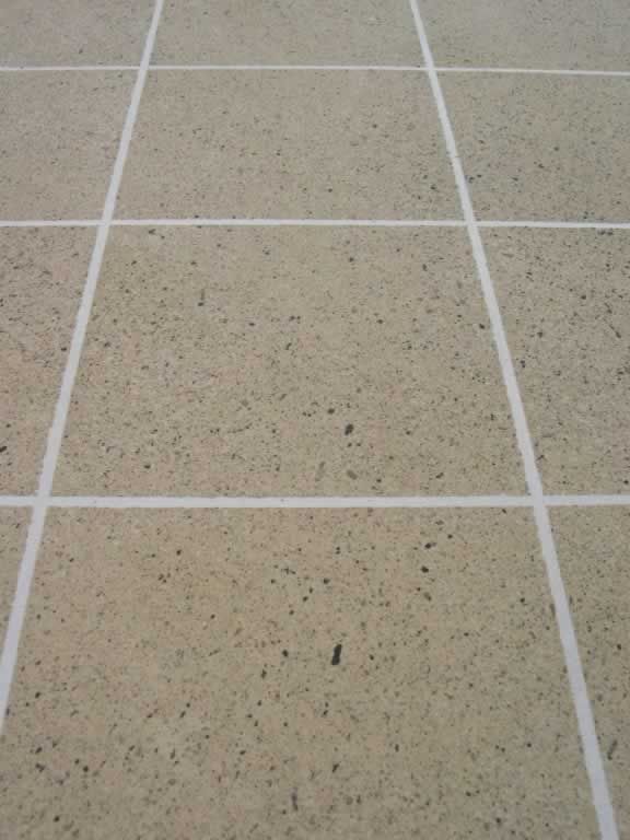 Beige speckled tile floor with white grout lines in a grid pattern