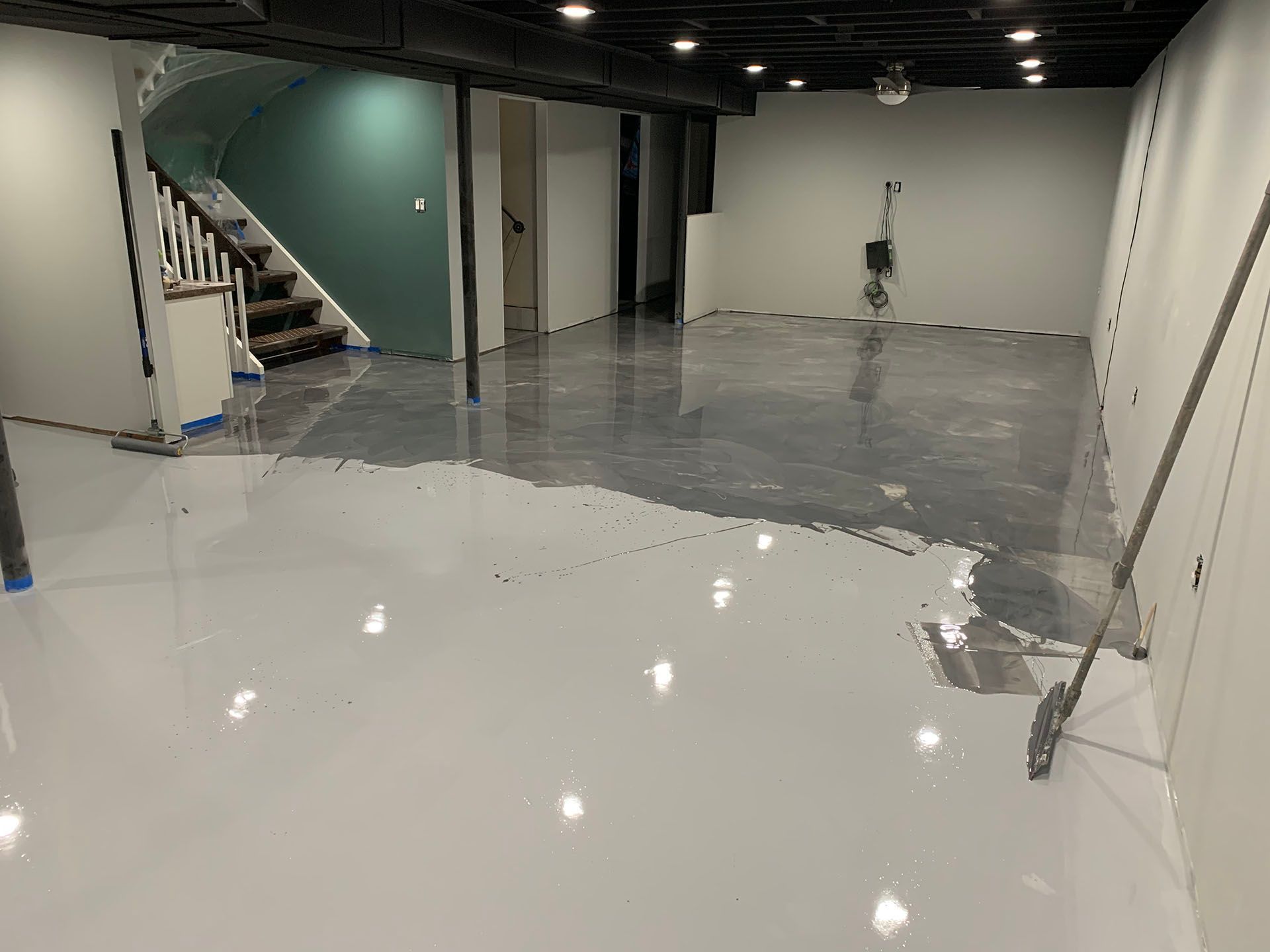 Empty indoor room with glossy white floor, gray walls, staircase, and a ladder on the right