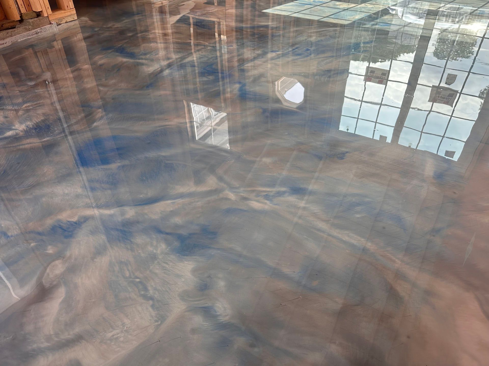 Reflective water-covered floor with window and ceiling reflections in a room
