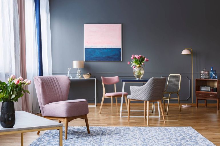 Modern living room with pink and gray chairs, dining table, flowers, and abstract wall art