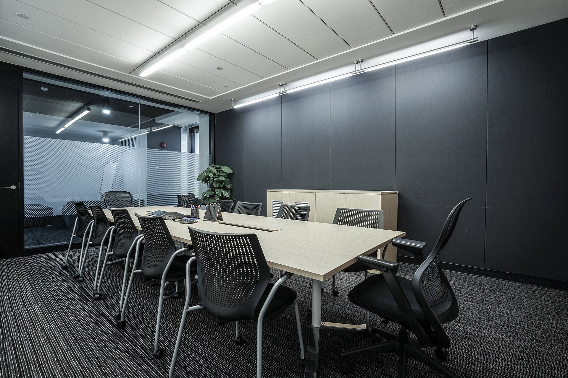 Modern conference room with long table, black chairs, and glass walls