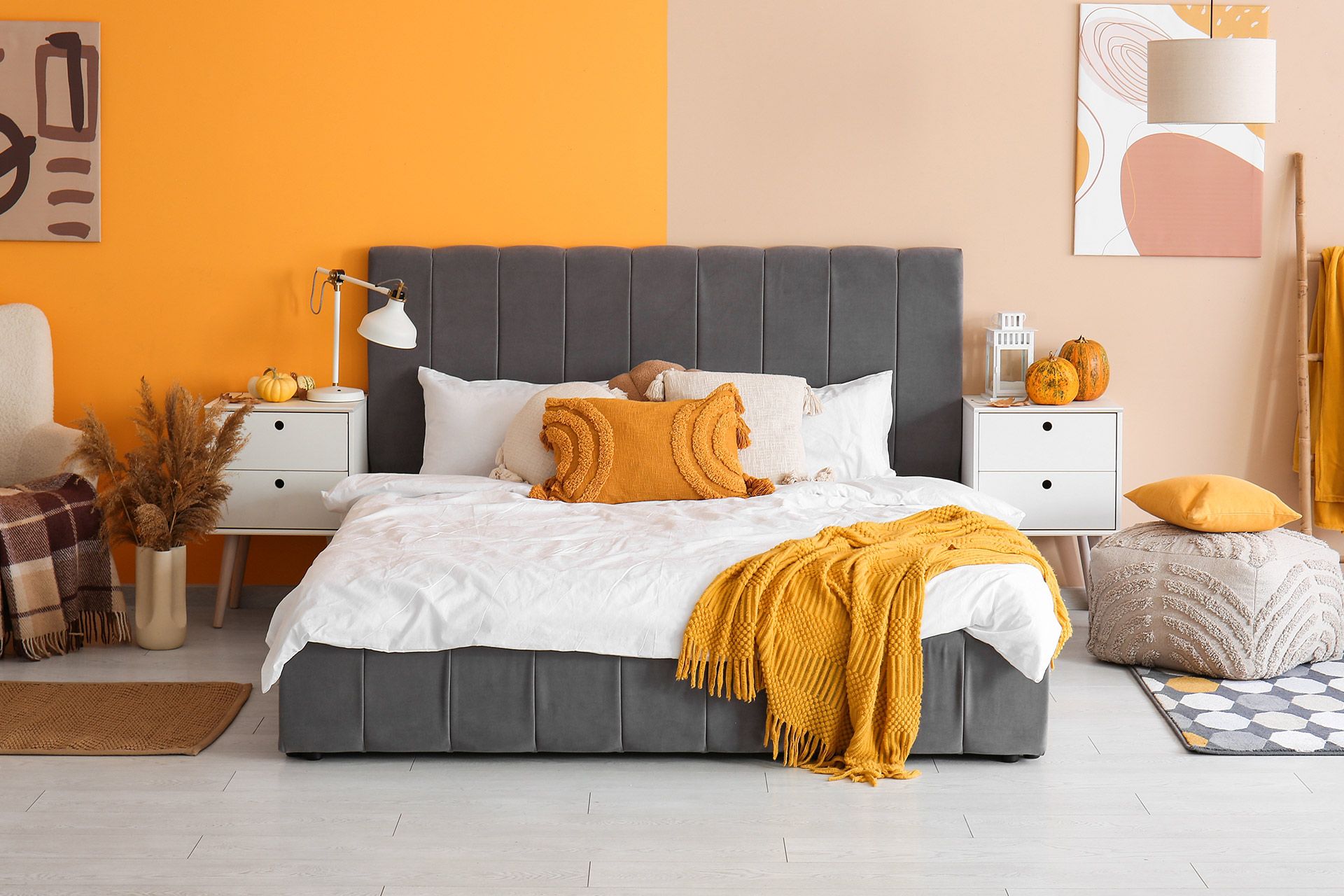Modern bedroom with a gray bed, white bedding, mustard accents, and peach walls