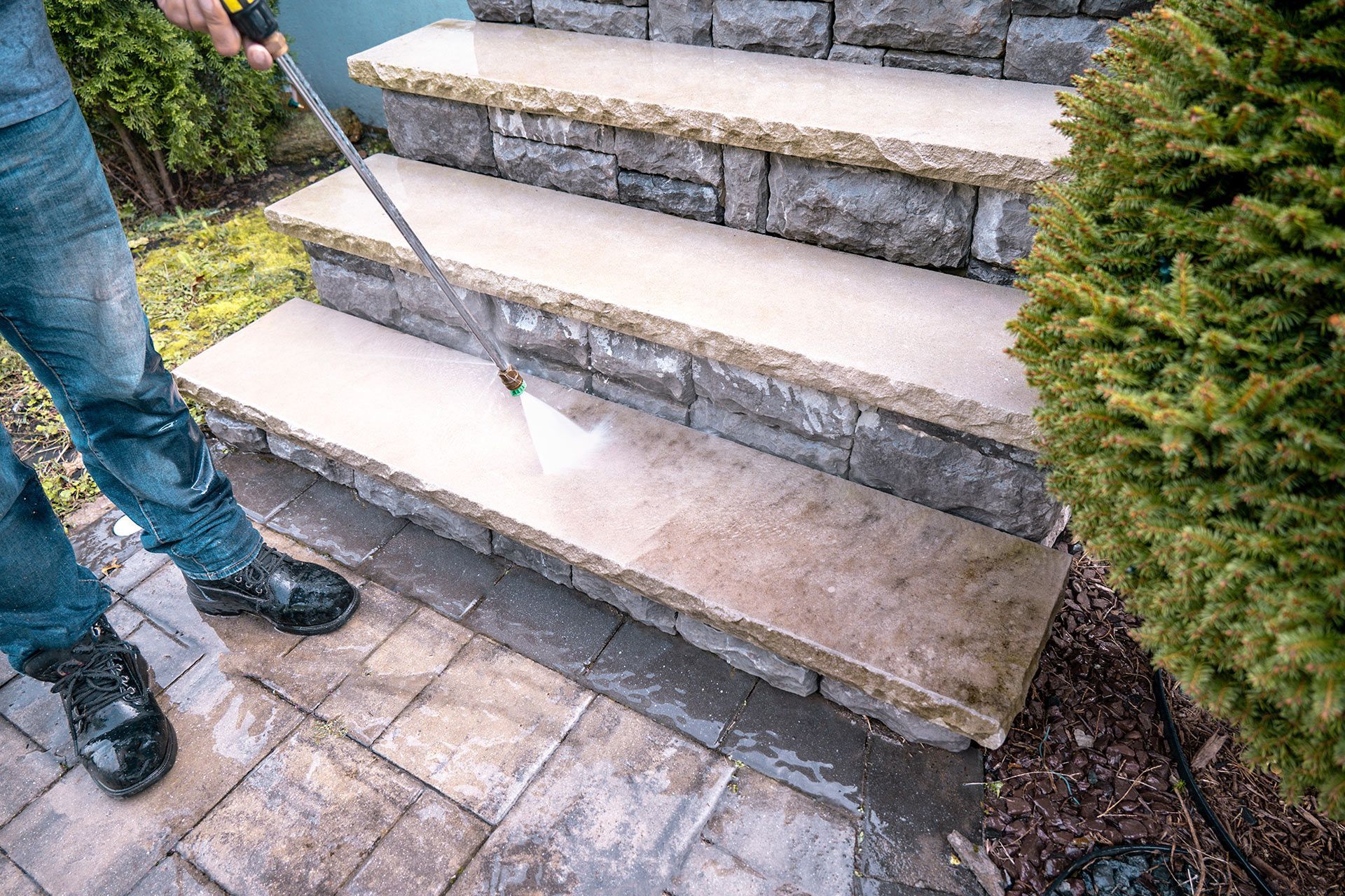 Stone outdoor steps beside a paved walkway, with a person’s legs visible at left.