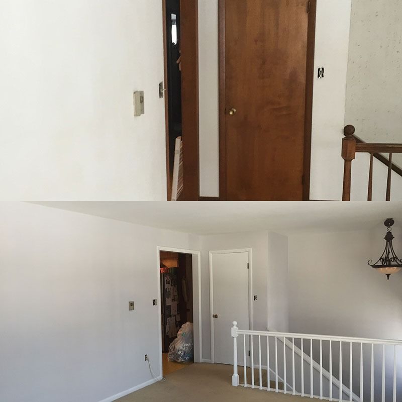 Interior hallway and landing with white walls, wooden doors, and a railing overlooking the lower floor.