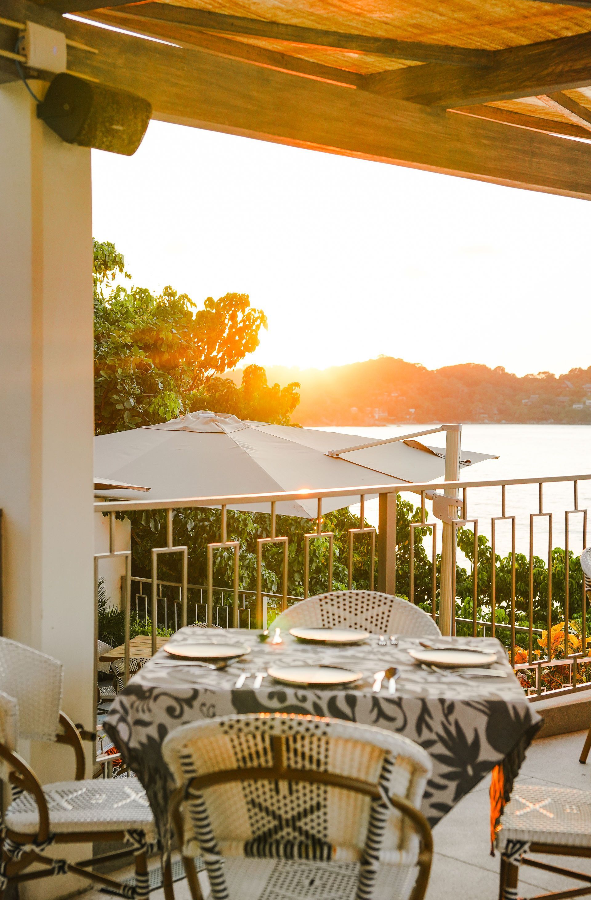 Sunlit patio with table and chairs overlooking a bright sunset and distant hills