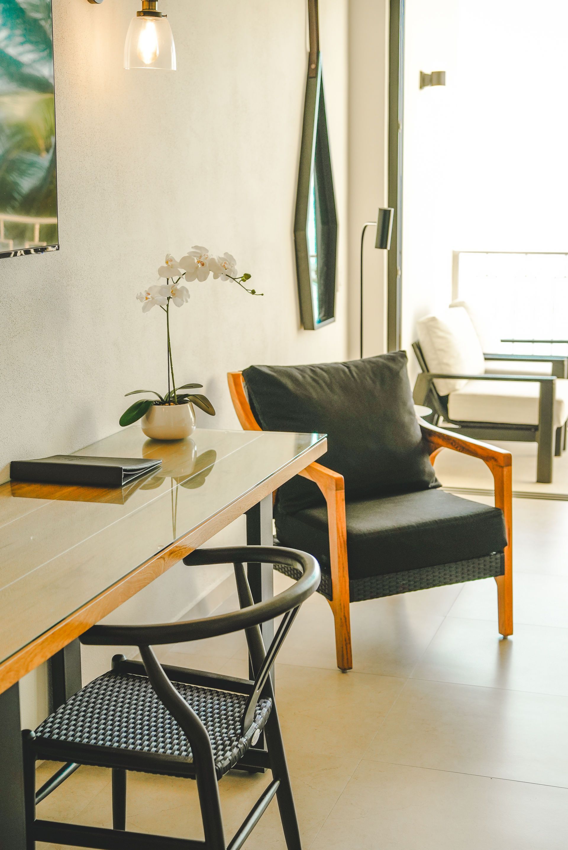Bright modern dining nook with black chairs, wooden table, pendant light, and a large window seat.