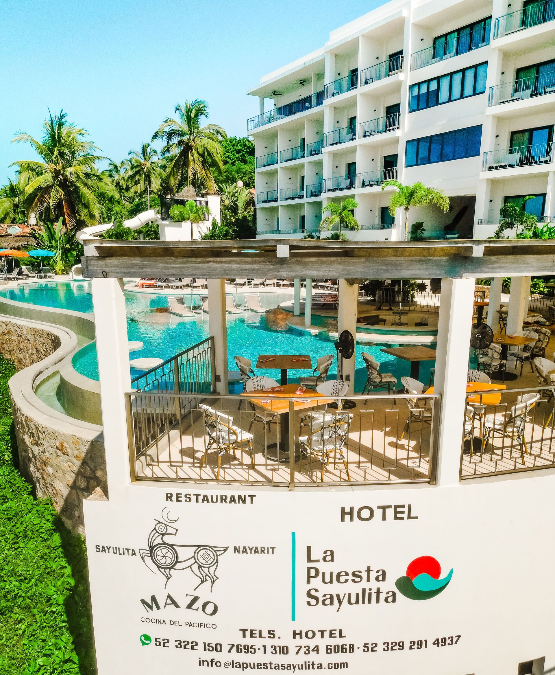 Hotel resort with turquoise pool, white balconies, palm trees, and “La Puesta Sargalita” sign.