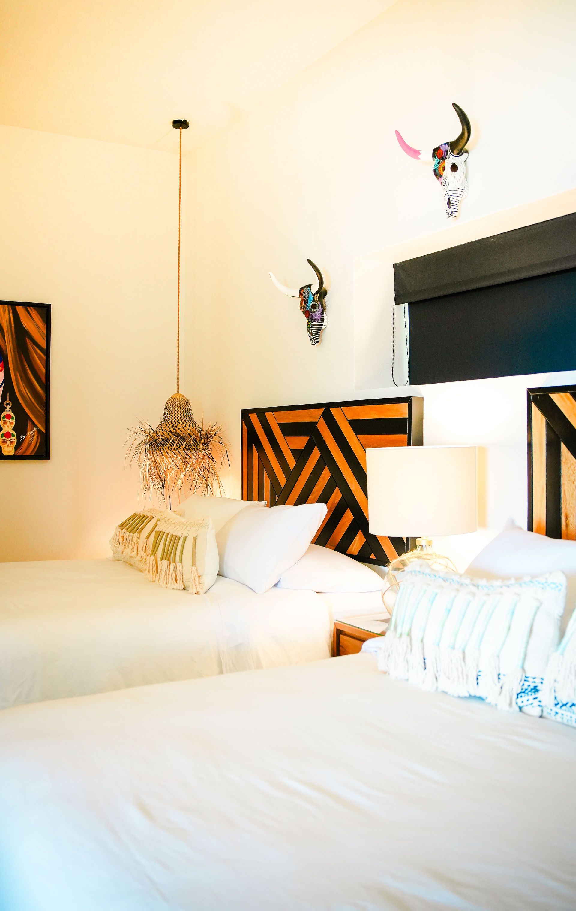 Bright bedroom with white bedding, a lit lamp, patterned headboard, and decorative wall accents.