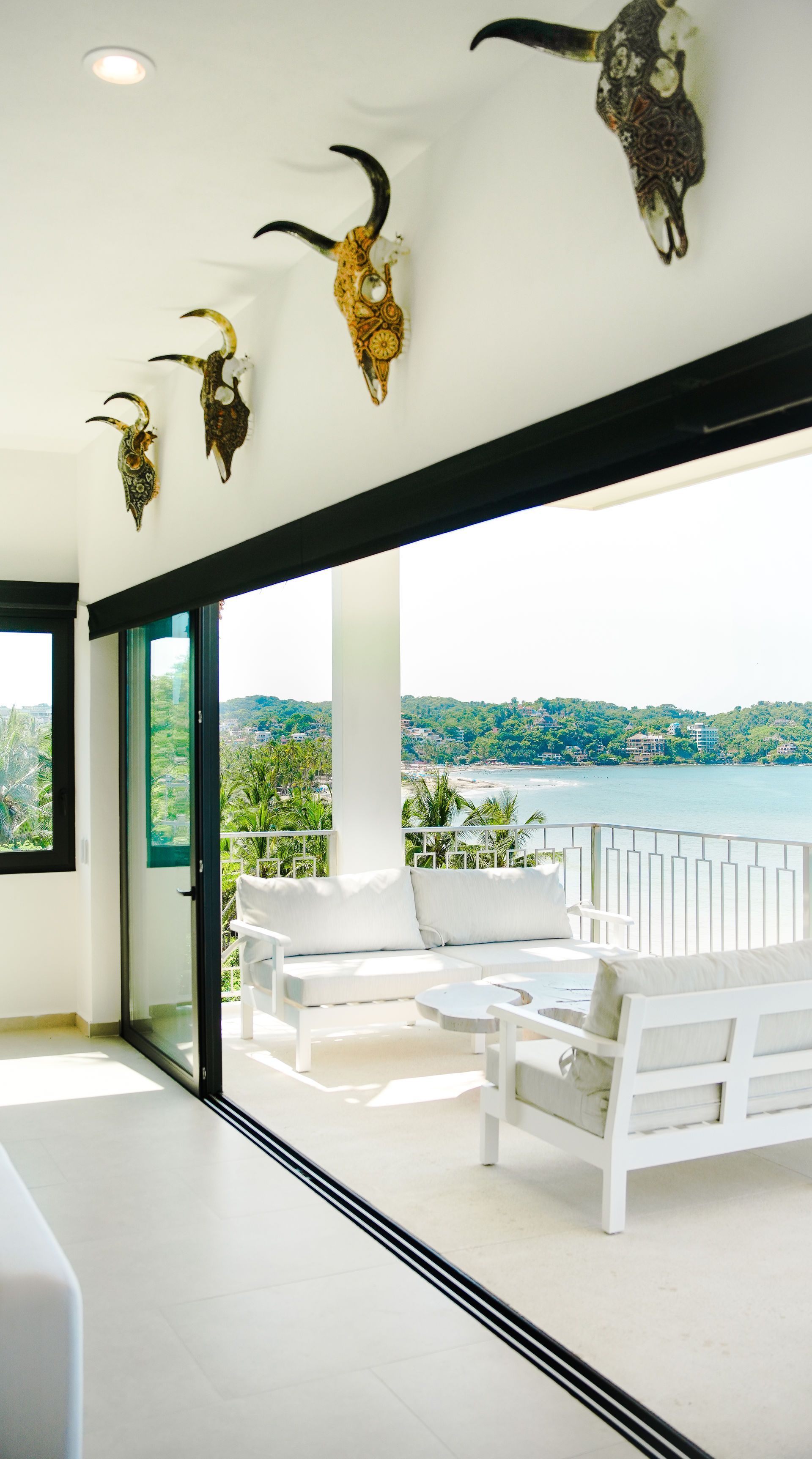 Bright lake-view porch with white bench seating and cow skull wall decor