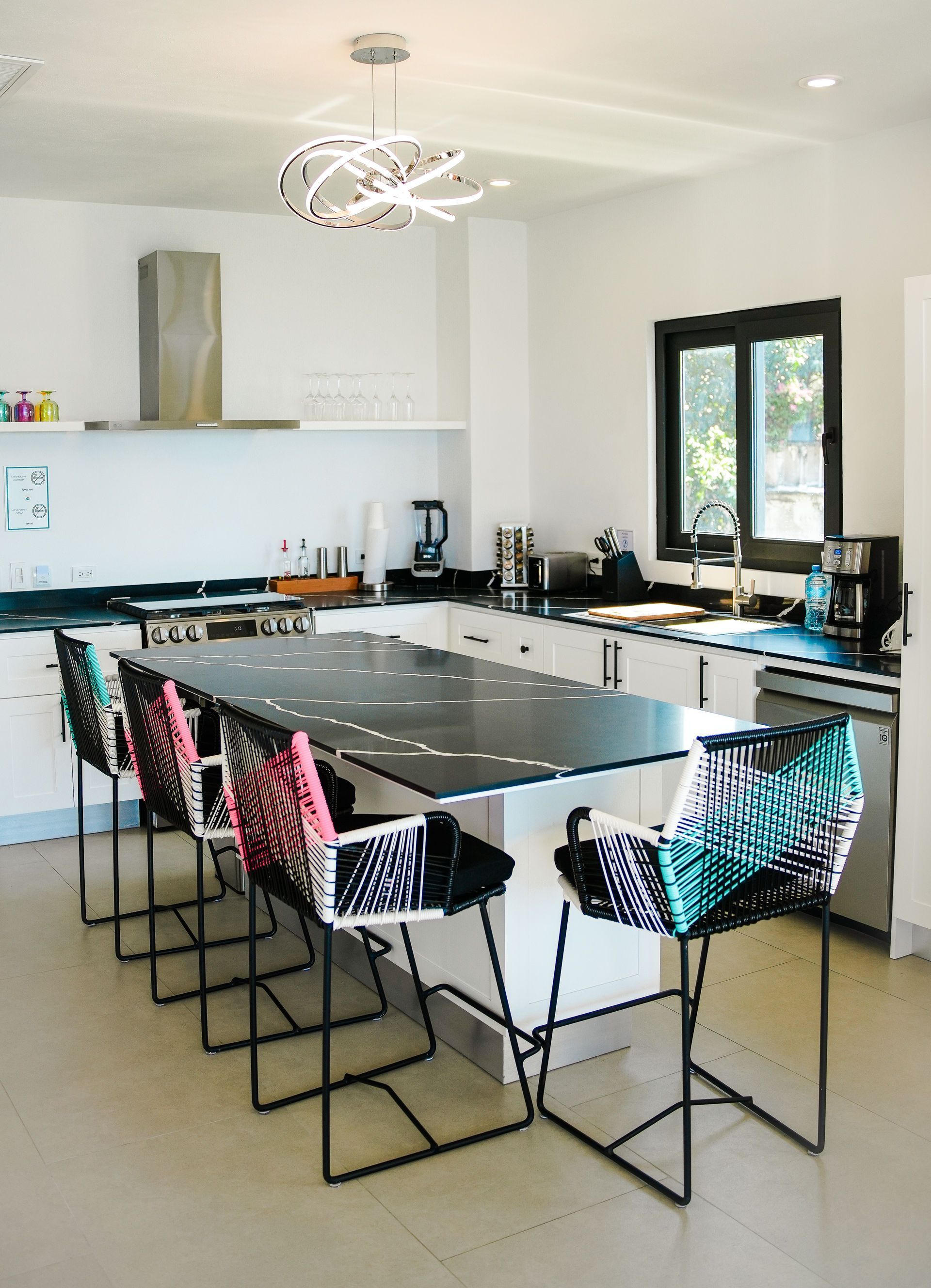 Modern kitchen with a large black island, bar stools, and white cabinets near windows