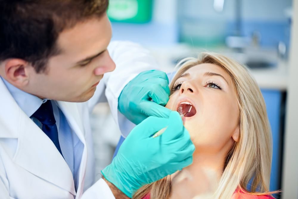 A Dentist Is Examining A Woman 's Teeth In A Dental Office — Dental Care Smithfield In Smithfield, QLD