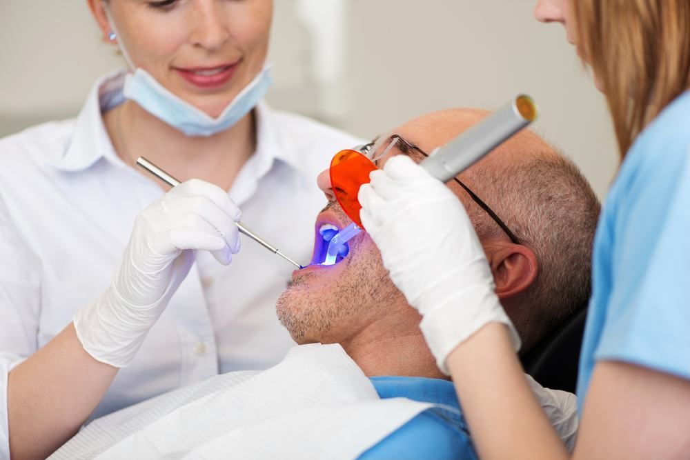 A Man Is Getting His Teeth Examined By A Dentist — Dental Care Smithfield In Smithfield, QLD