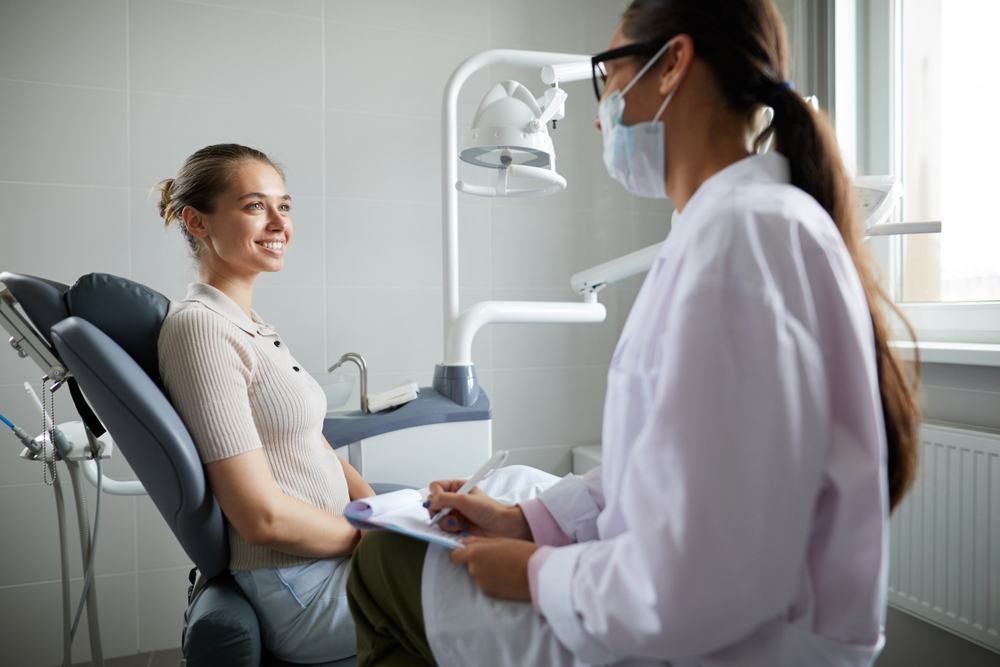 A Pregnant Woman Is Sitting In A Dental Chair Talking To A Dentist — Dental Care Smithfield In Smithfield, QLD