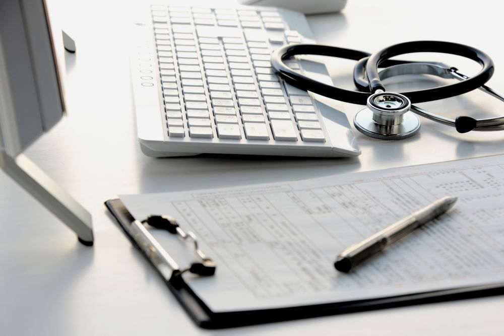 A Stethoscope Is Sitting On Top Of A Clipboard Next To A Computer Keyboard — Dental Care Smithfield In Smithfield, QLD