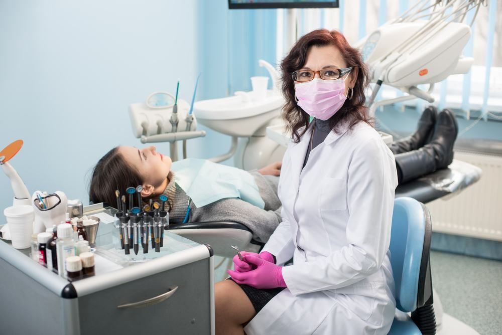 A Female Dentist Is Sitting Next To A Patient In A Dental Chair — Dental Care Smithfield In Smithfield, QLD