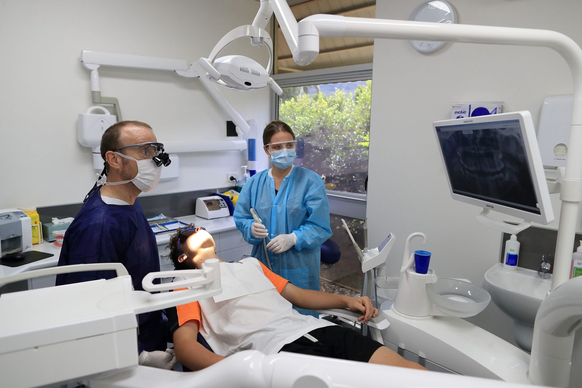 A Woman Wearing Glasses And A Watch Is Smiling For The Camera — Dental Care Smithfield In Smithfield, QLD
