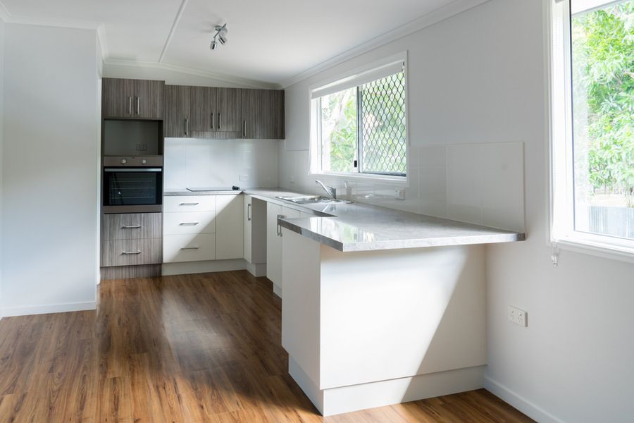 An Empty Kitchen With White Cabinets and Wooden Floors — Bruce Smith Cabinets in Pottsville, NSW