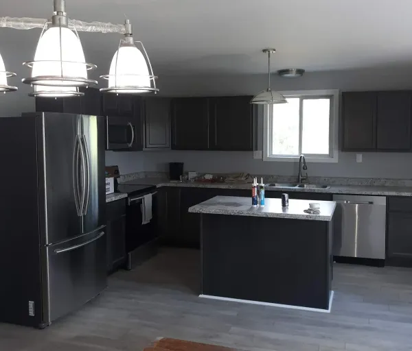 A kitchen with black cabinets and stainless steel appliances