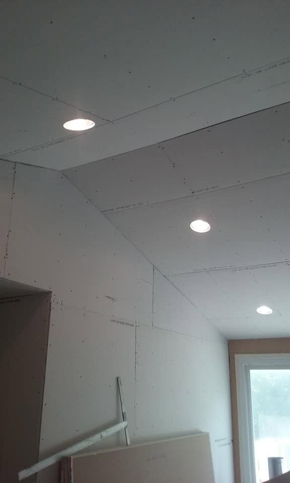 White room ceiling with recessed lights and a window, seen above a cabinet or shelf.