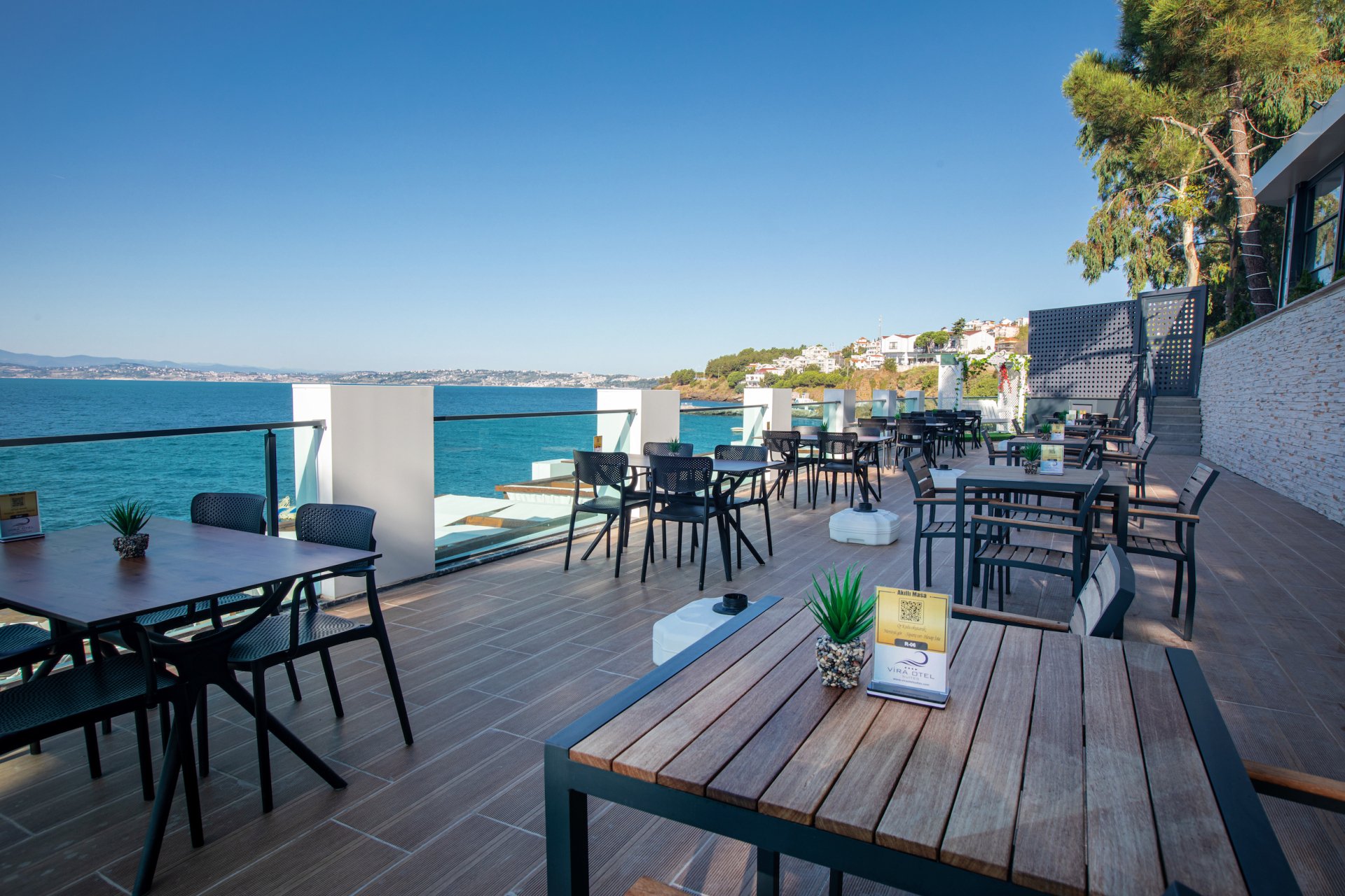 Okyanusa bakan masa ve sandalyelerle donatılmış bir veranda.