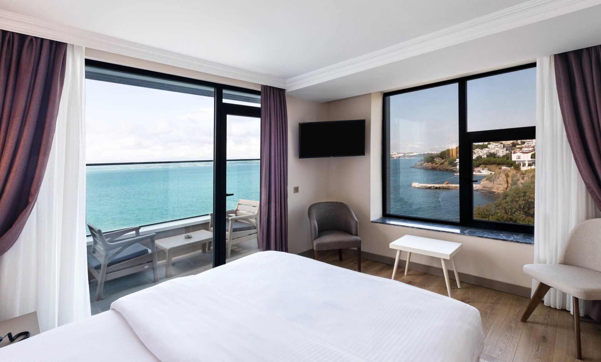 Büyük bir yatağa ve okyanus manzarasına sahip bir otel odası.