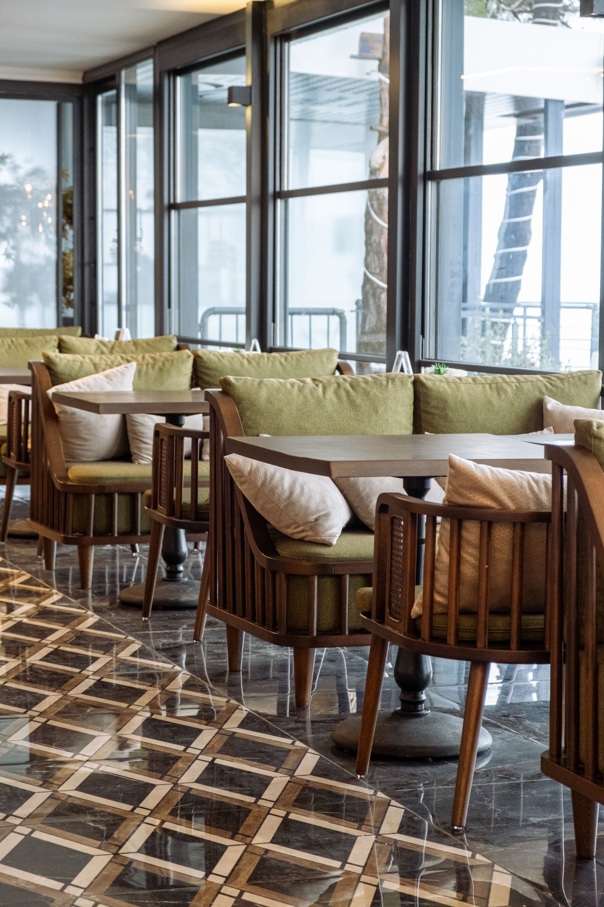 Masaları, sandalyeleri ve mermer zemini olan bir restoran.