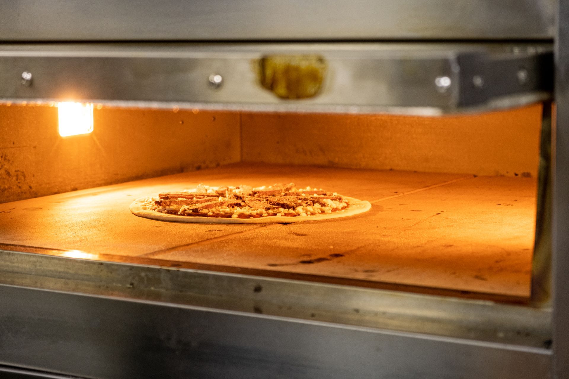 Kapısı açık bir fırında pizza pişiriliyor