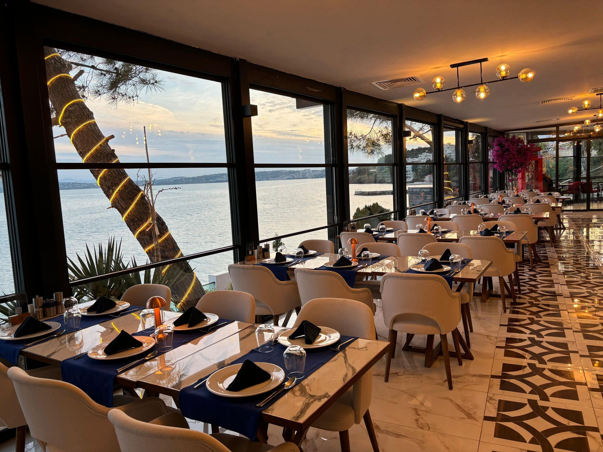 Masaları ve sandalyeleri olan, okyanus manzaralı bir restoran.