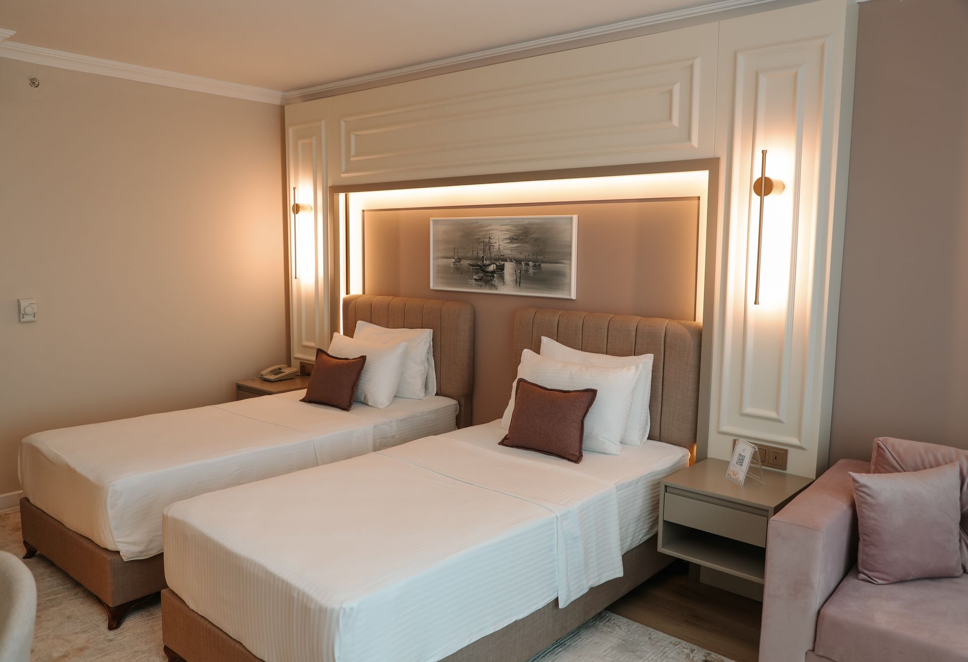 Iki yataklı ve bir kanepeli otel odası.