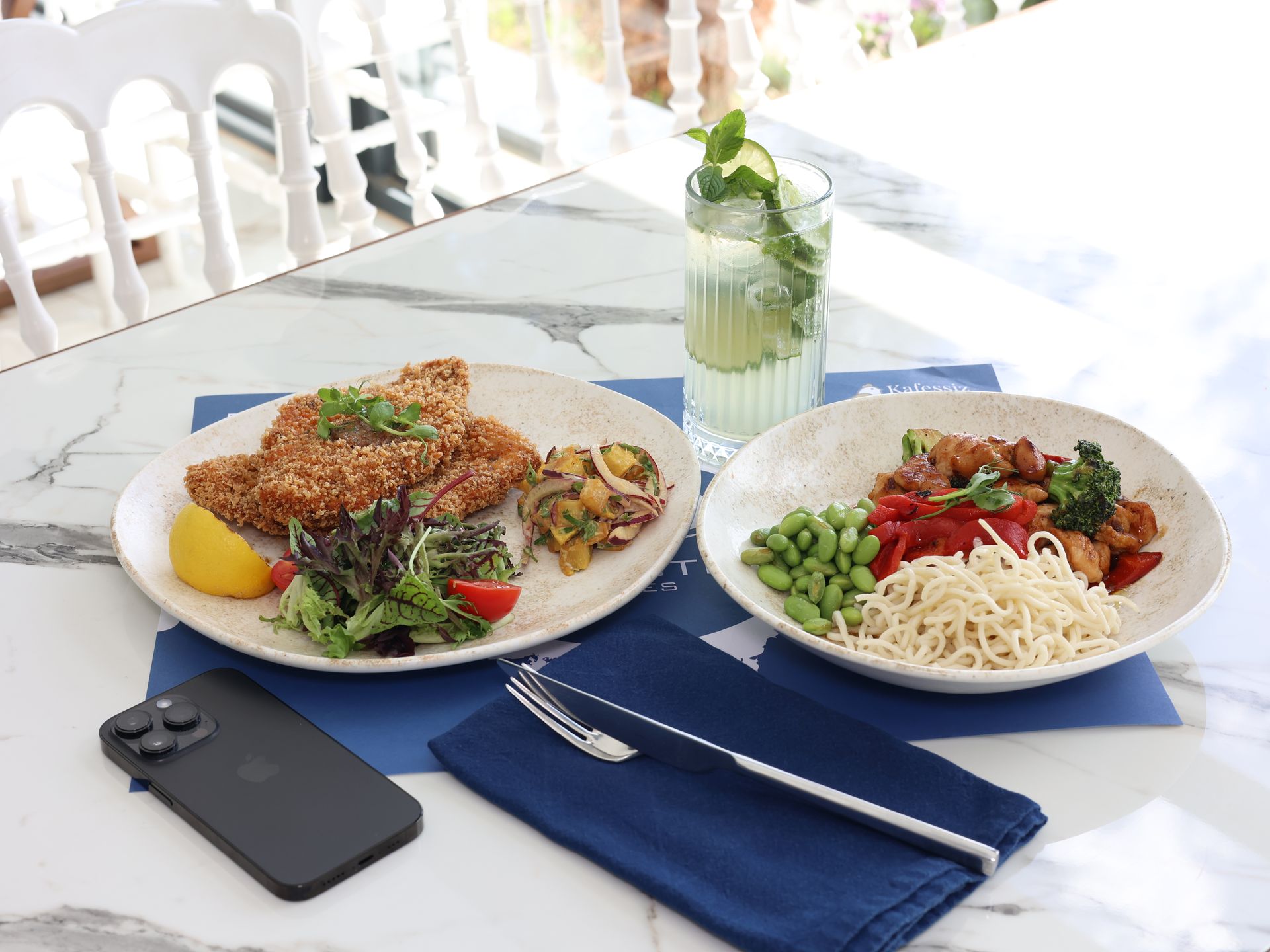 Üzerinde yemek tabakları ve bir cep telefonu bulunan bir masa.