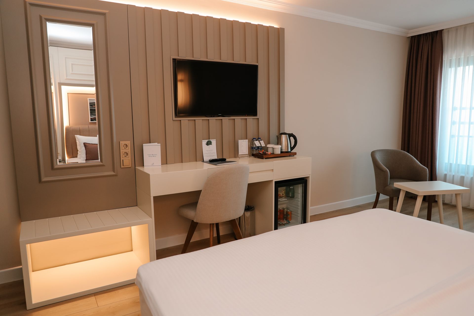 Yatak, çalışma masası, sandalye ve televizyonun bulunduğu bir otel odası.