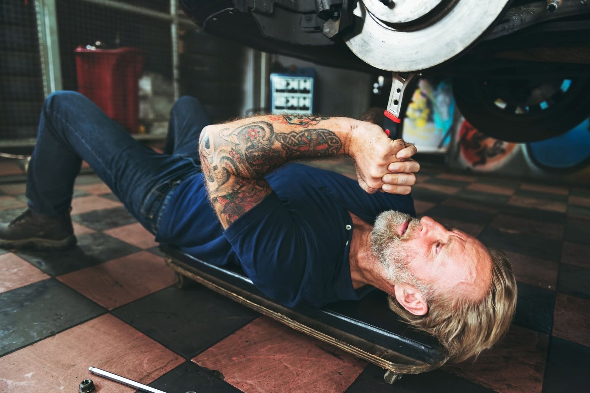 Person lying under a car, using a jack to lift it in a garage | Frontier Auto Center